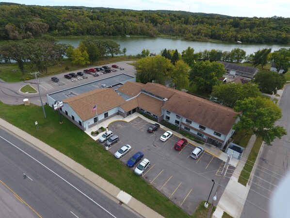 A building with a parking lot, a flag, and a view of a lake.