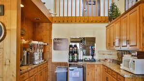 A kitchen with wooden cabinets, a waffle maker, and a coffee station.