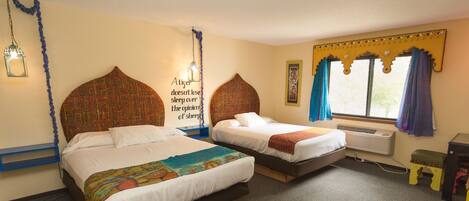 A hotel room with two beds, a wall-mounted air conditioner, and a window with curtains.