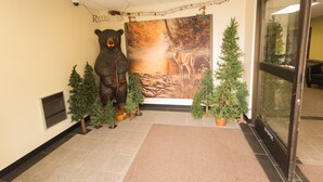 A lobby with a bear statue, a mural, and Christmas trees.