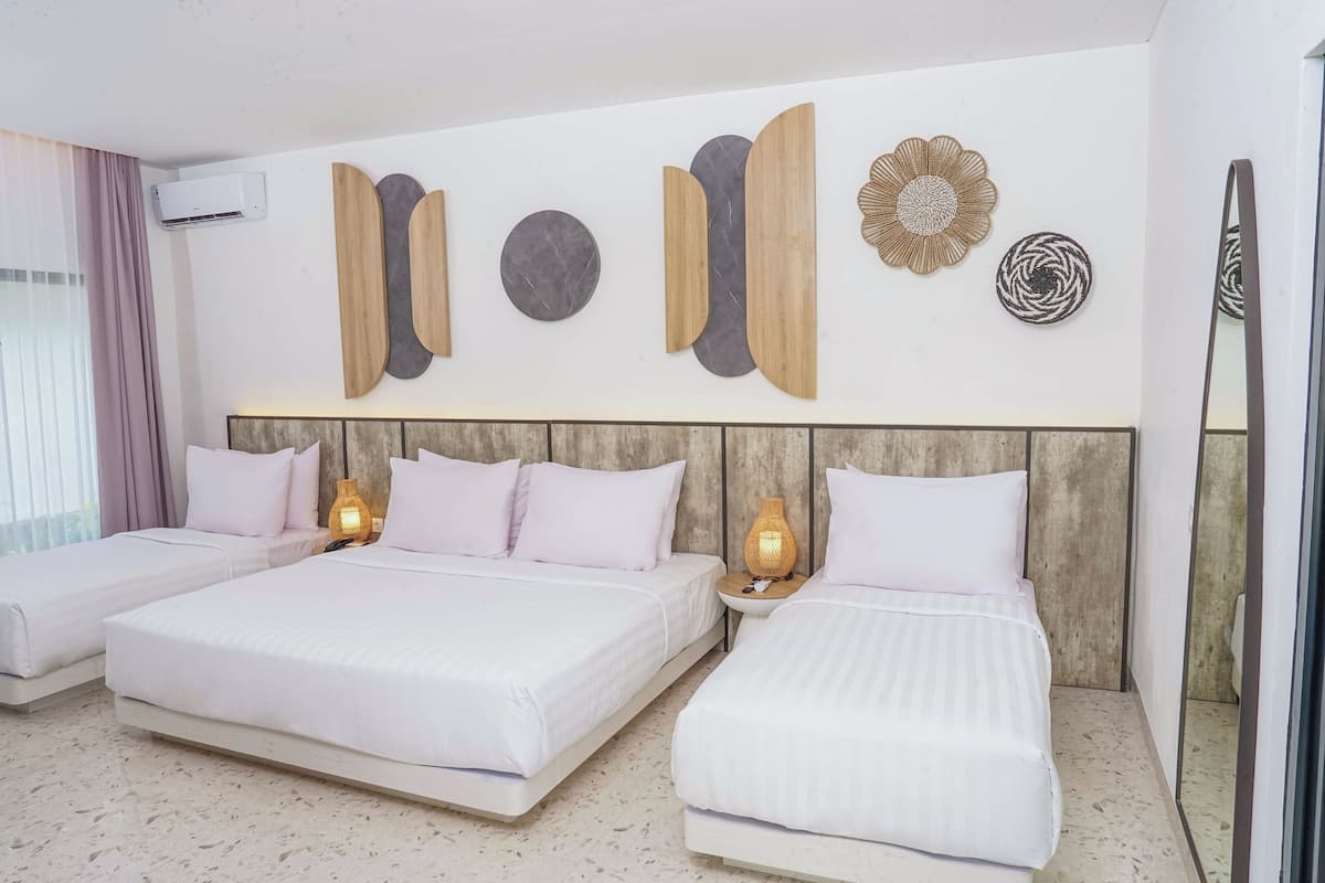A hotel room with two beds, a wall-mounted air conditioner, and decorative wall art.