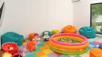 A colorful play area with a ball pit, bean bags, and various toys.