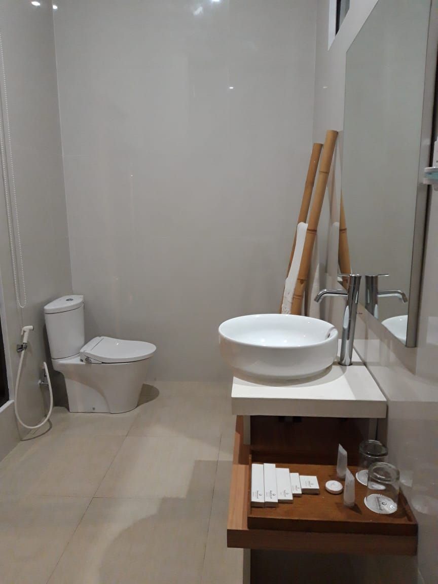A modern bathroom with a toilet, bidet, and a sink with a mirror above it.