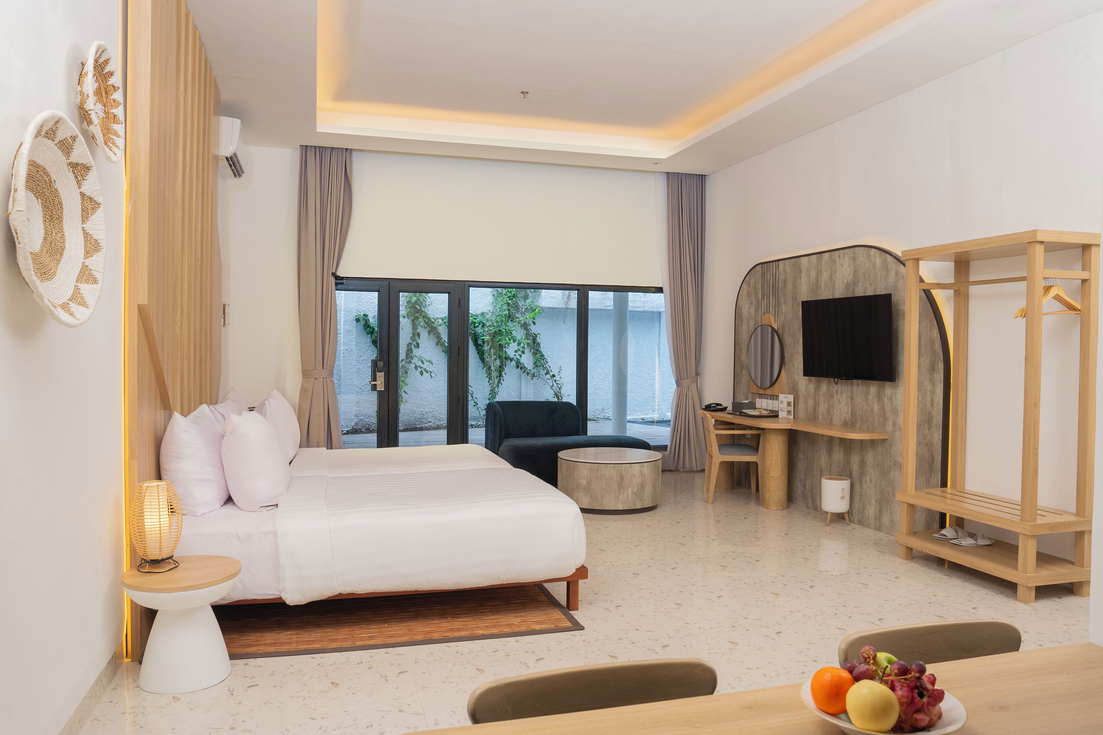 A modern hotel room with a bed, a desk, a chair, a TV, and a view of the outdoors.
