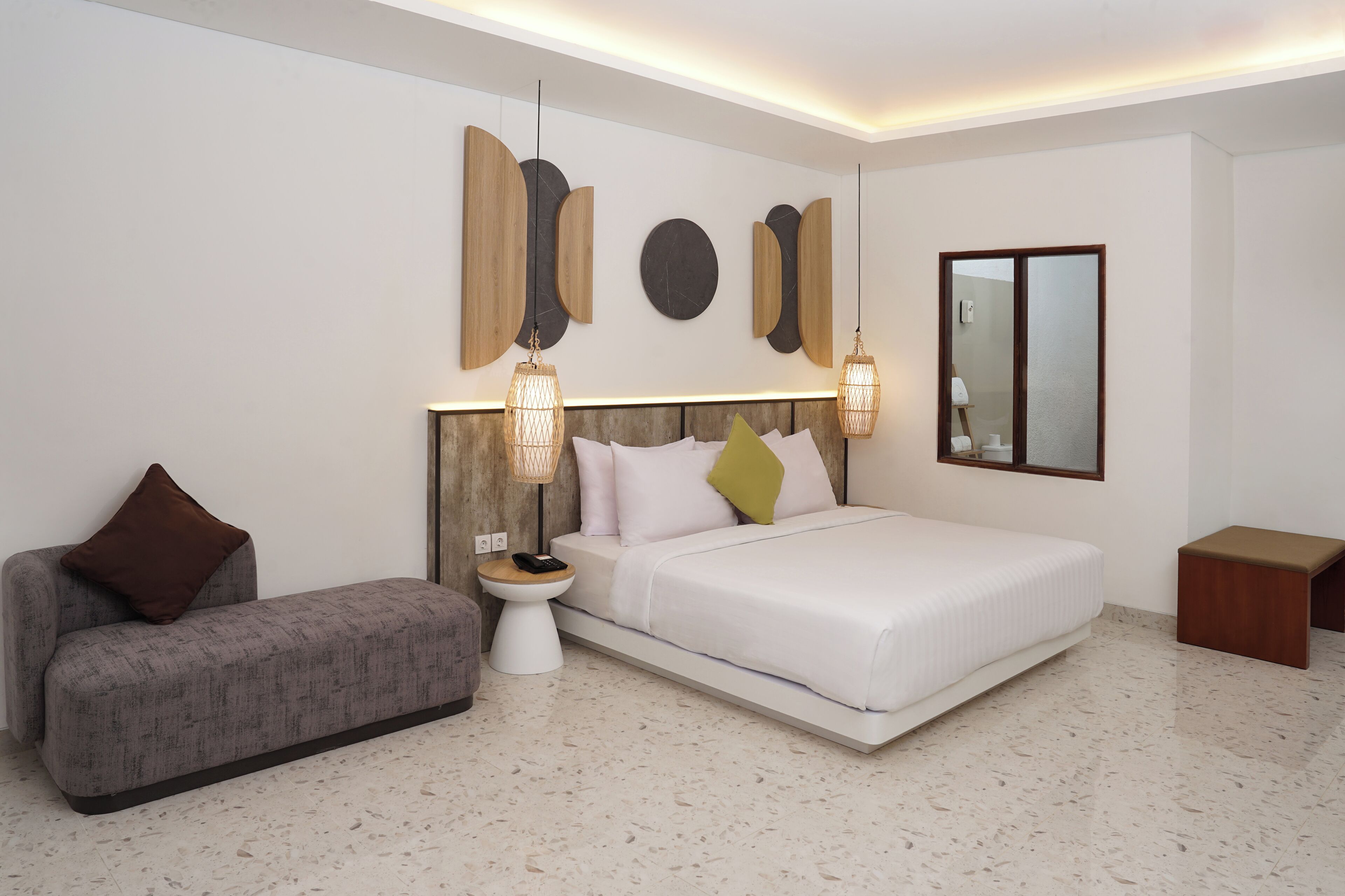 A modern bedroom with a bed, a sofa, a nightstand, and wall art.