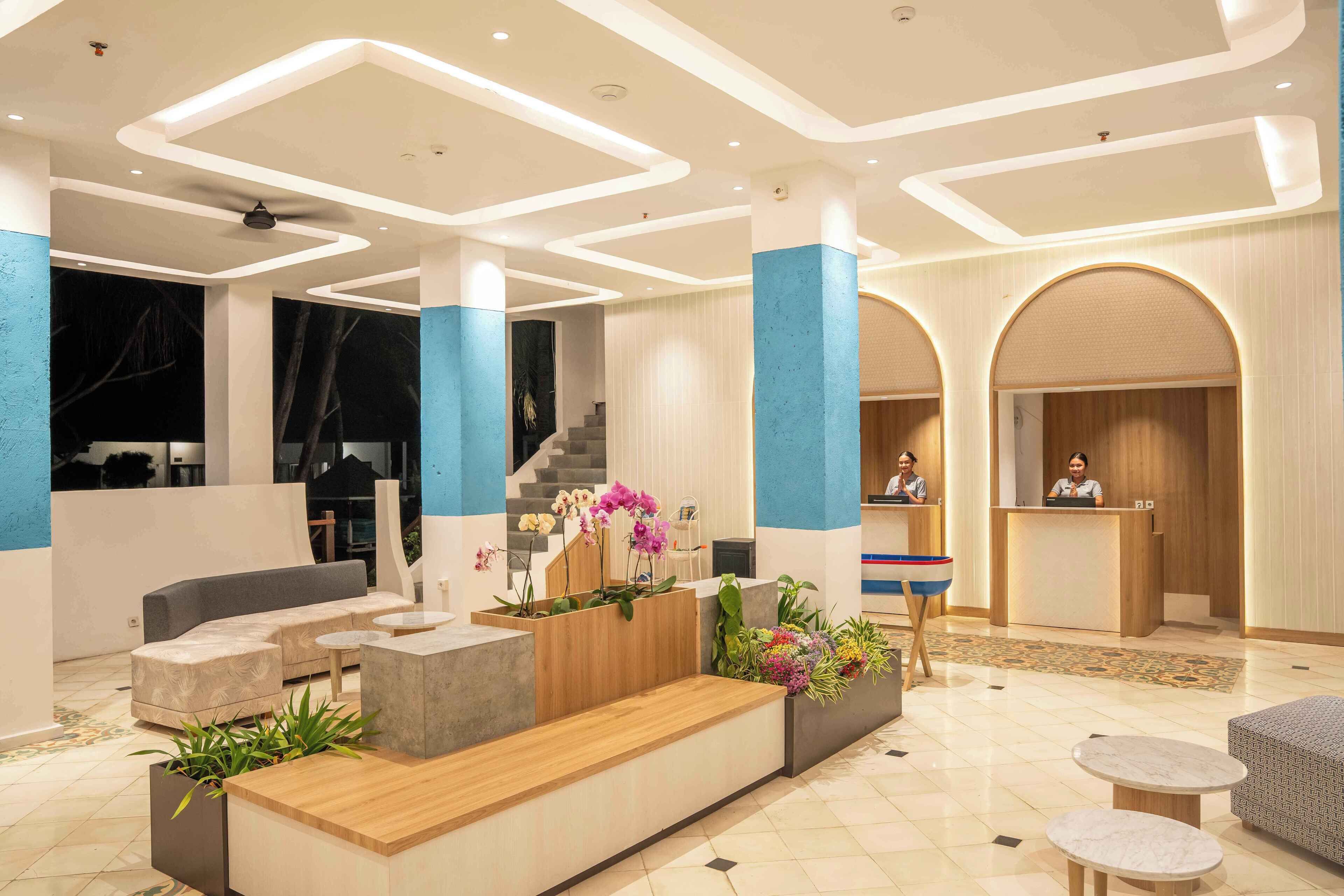 Een moderne lobby met een receptiebalie, een zithoek en een trap.