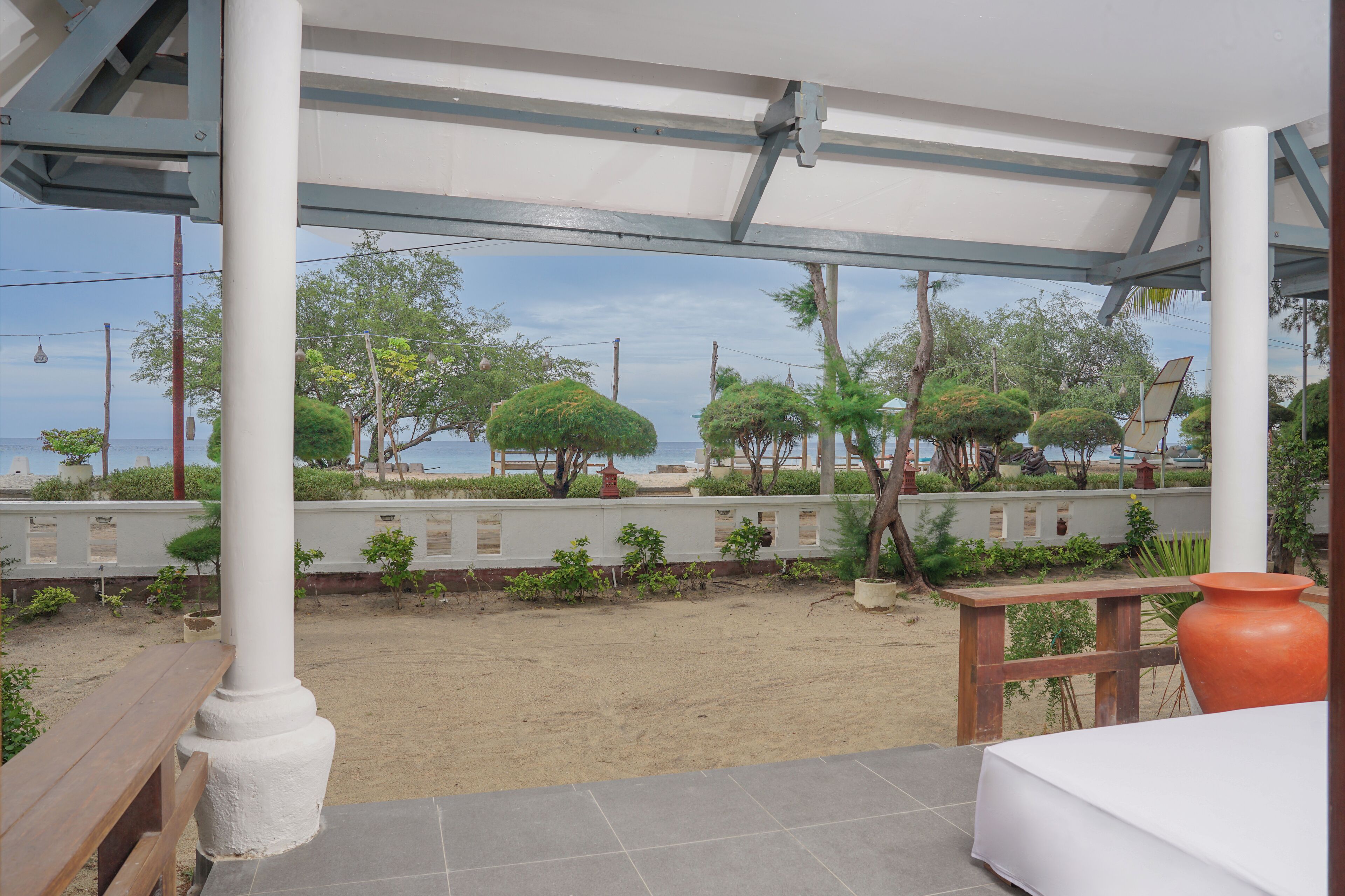 Un espacio al aire libre cubierto con una playa de arena, bancos de madera y vistas al mar.