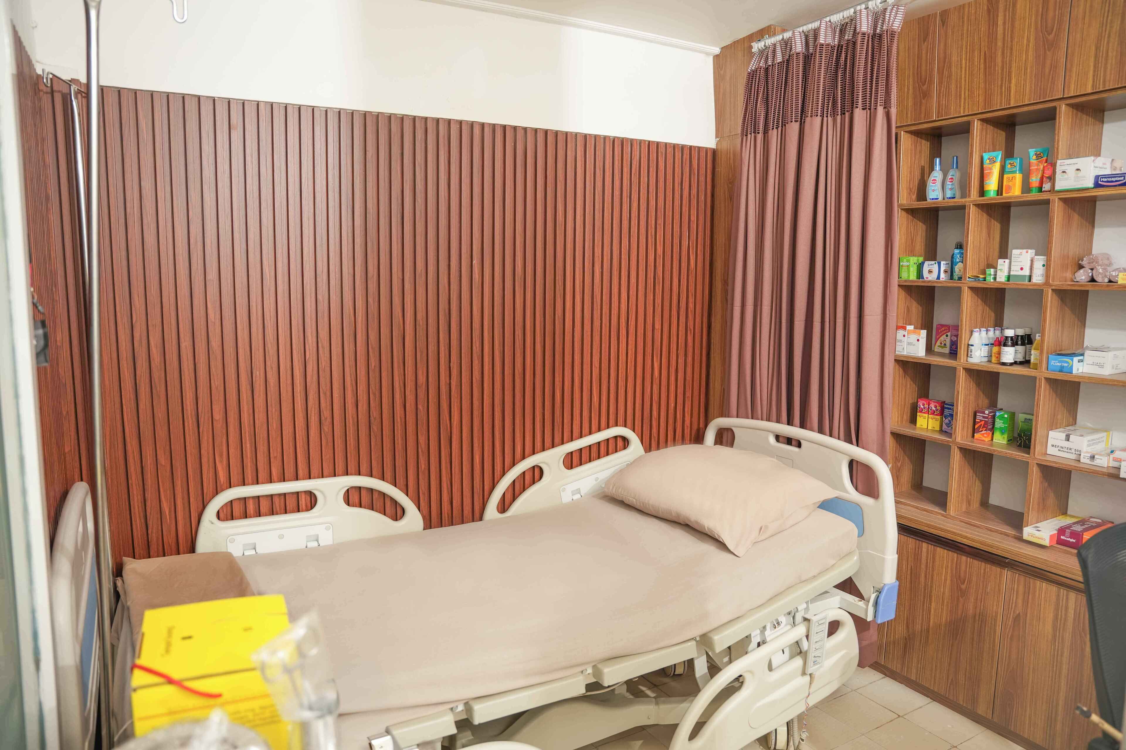 A hospital room with a bed, wooden paneling, and a shelf with medical supplies.