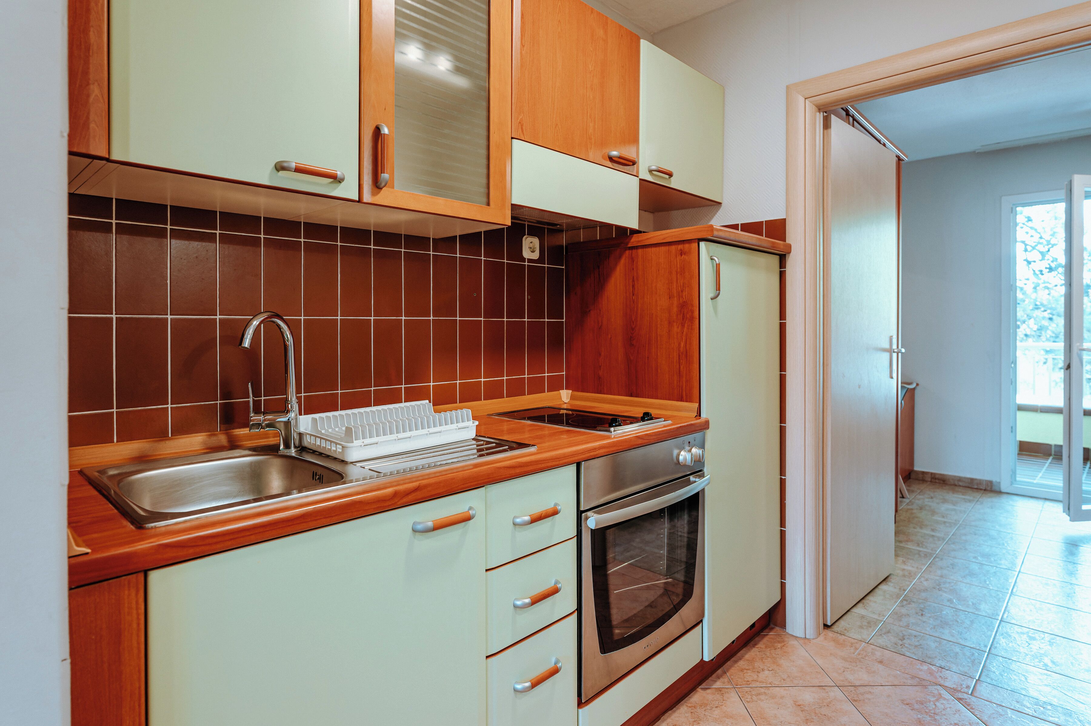 Una cocina con armarios de madera, un lavamanos de acero inoxidable y un horno empotrado.