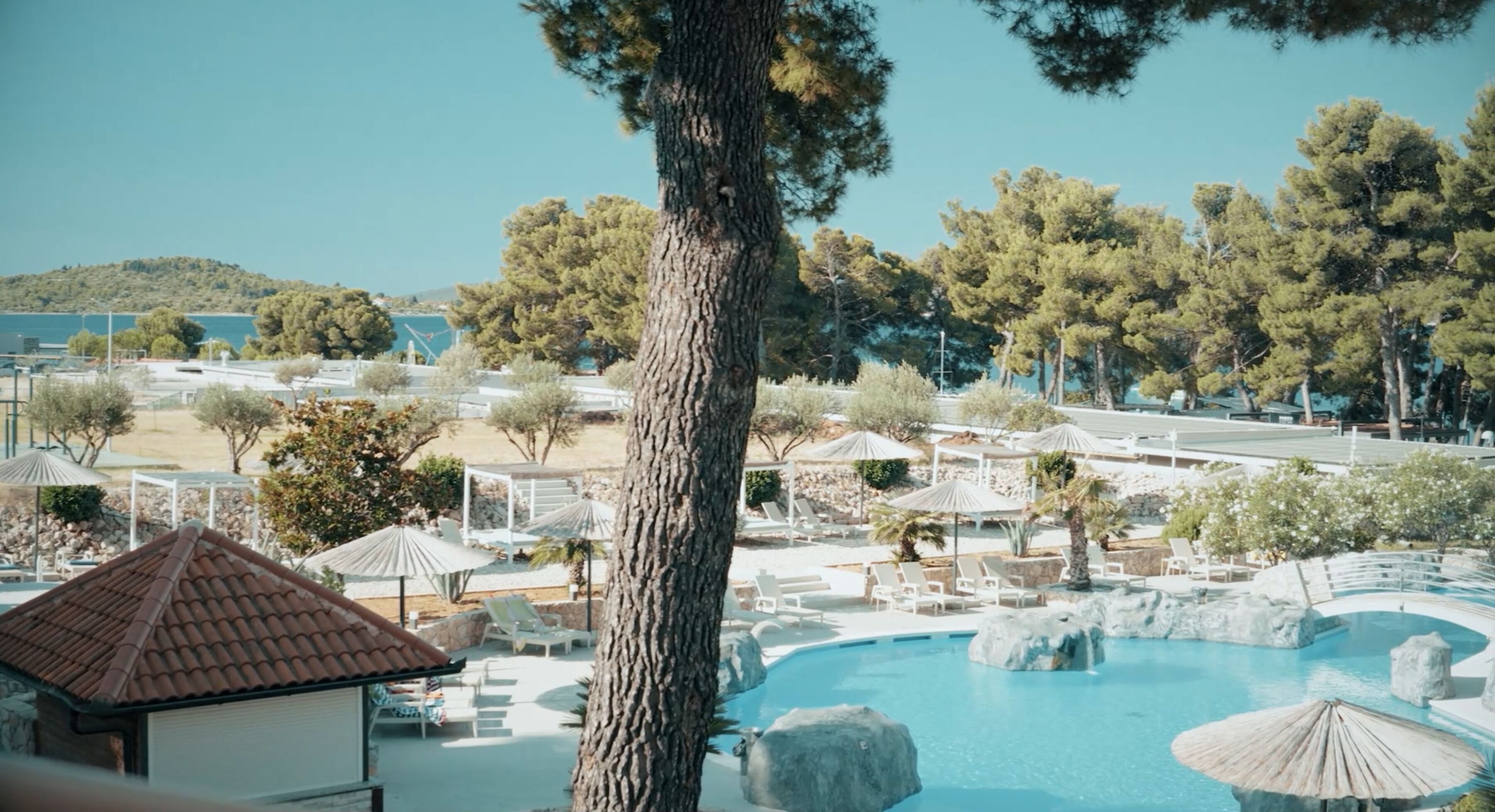 A resort with a swimming pool, lounge chairs, and umbrellas.