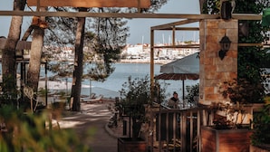 A coastal walkway with outdoor seating, a stone wall, and a view of the marina and boats. - Matilde Beach Resort (Vodice)
