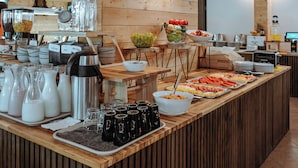 A buffet setup with various food items and beverages, wooden paneling, and hanging pendant lights. - Matilde Beach Resort (Vodice)