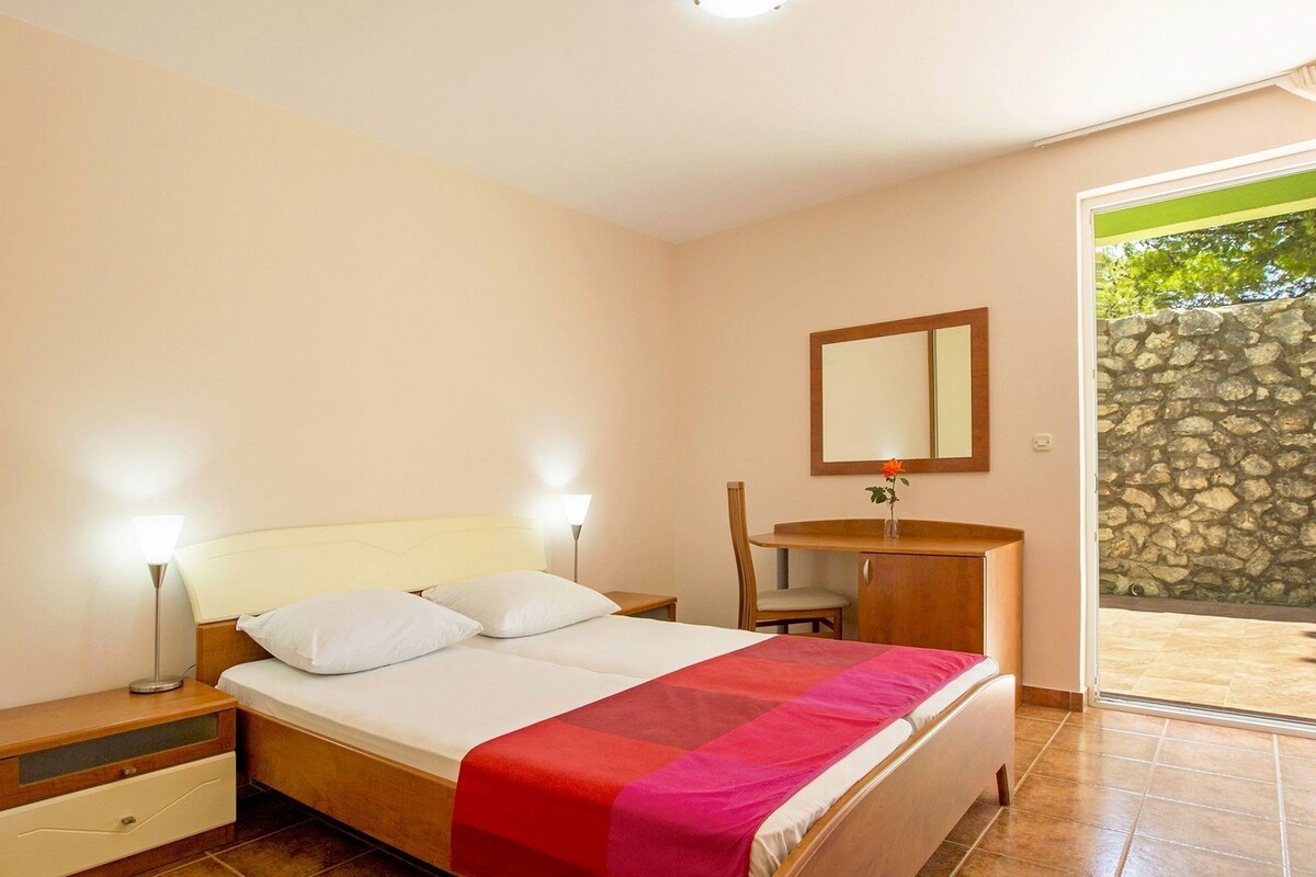 A bedroom with a bed, bedside tables, a mirror, and a small desk with a chair.