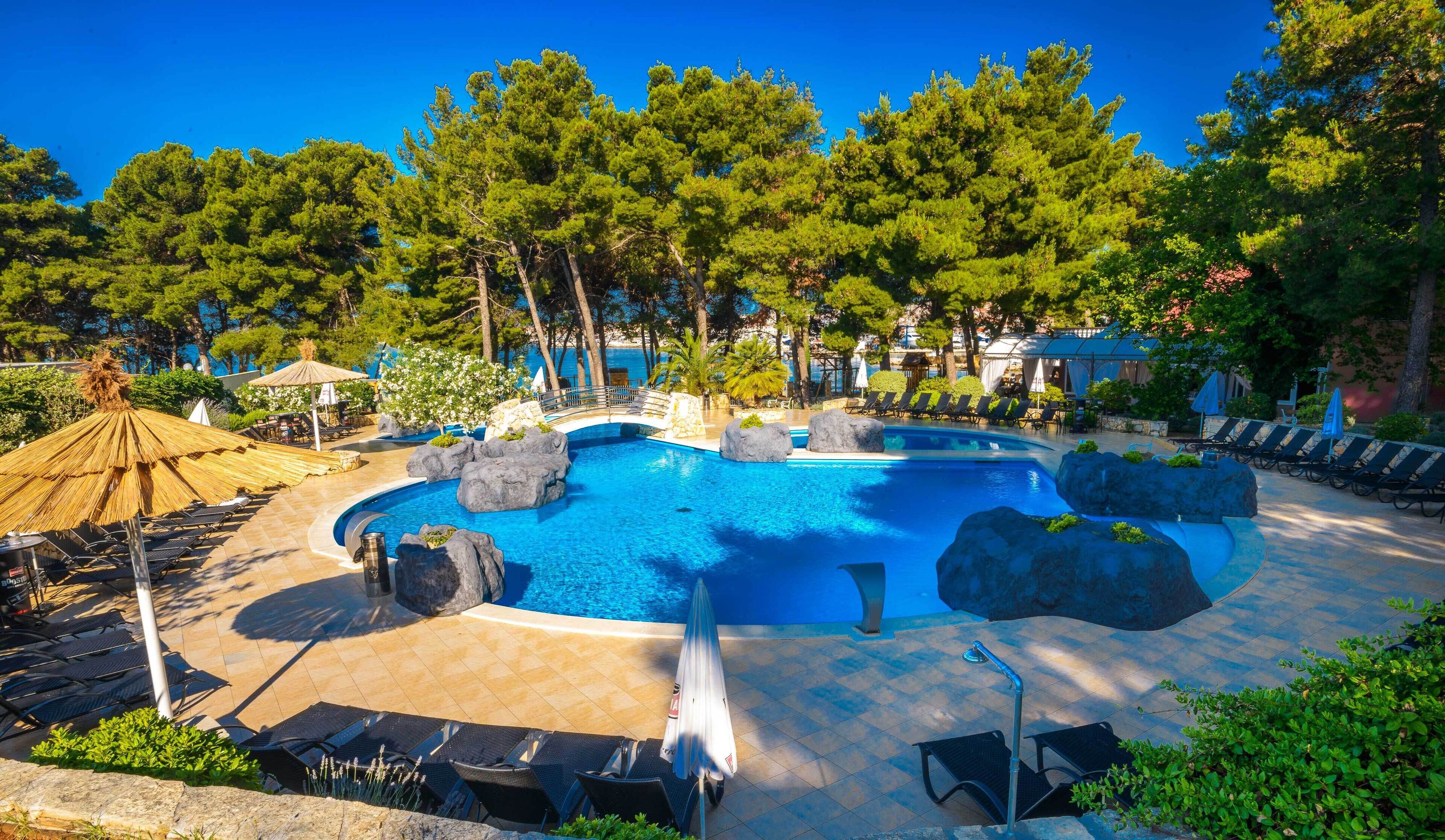 En säsongsöppen utomhuspool, parasoller och solstolar