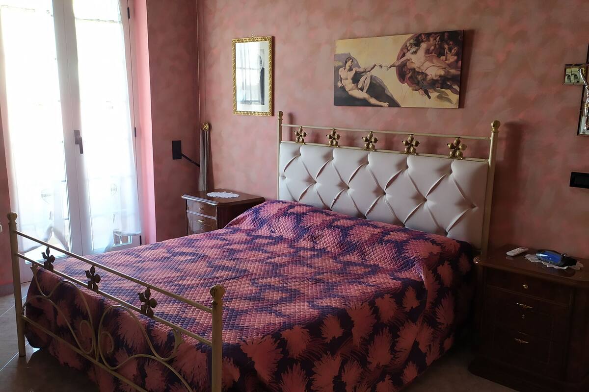 A bedroom with a bed, a nightstand, a dresser, a mirror, and a painting on the wall.