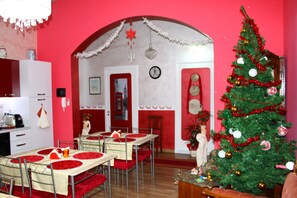 Un coin repas avec des tables dressées pour quatre personnes, un sapin de Noël et une décoration aux couleurs rouge et blanche.