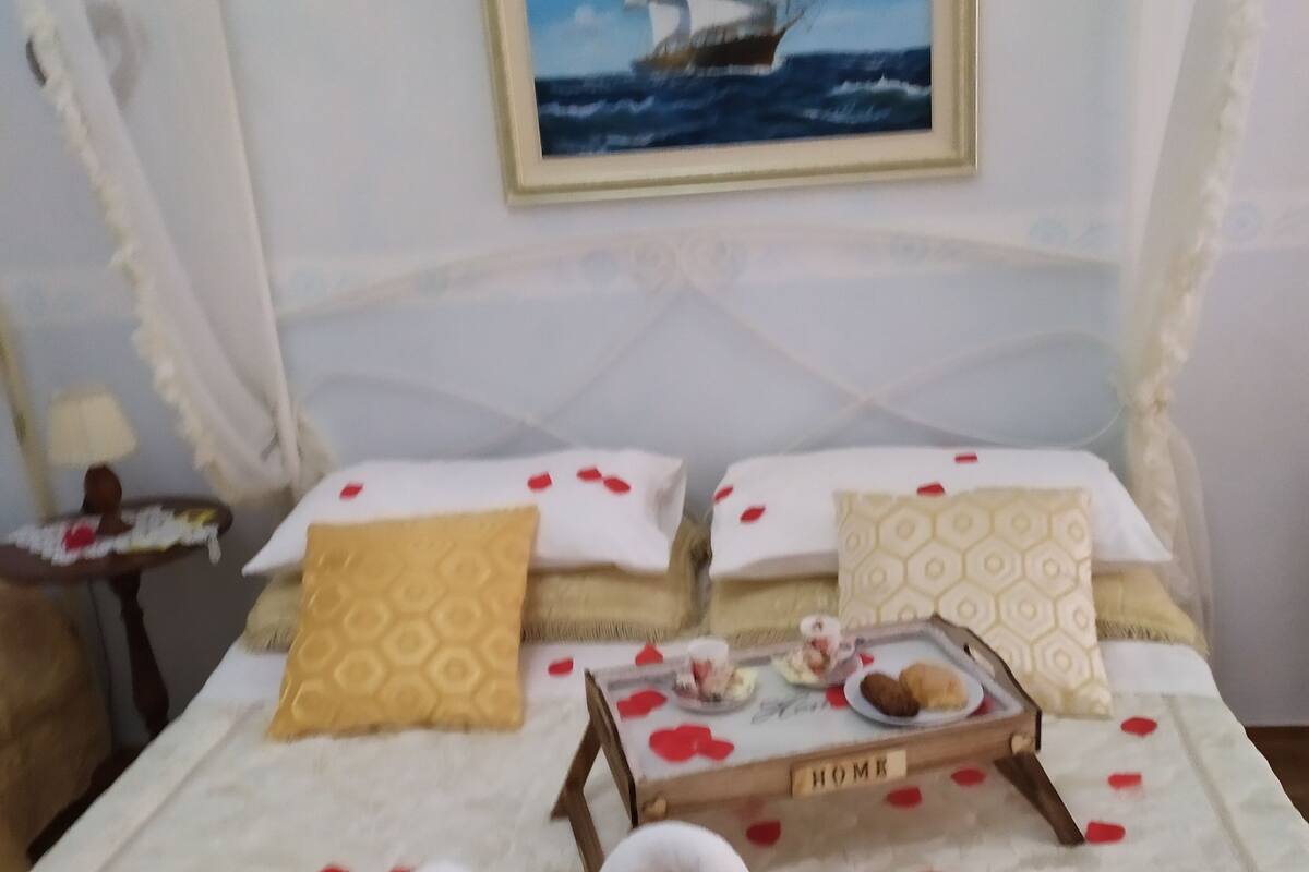 A hotel room with two beds, a painting of a ship on the wall, and a tray with a towel and a bottle on the bed.