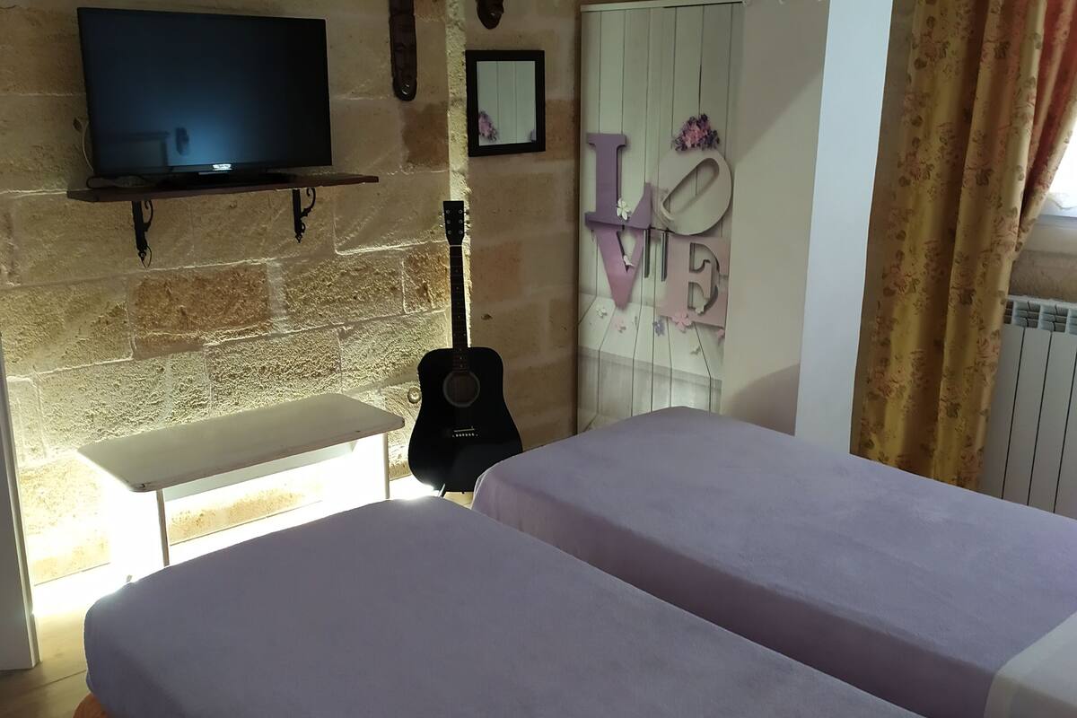 A room with two beds, a television, a guitar, and a 'I LOVE' sign on the wall.