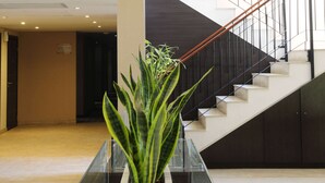 A modern indoor space with a staircase, a potted plant, and a sign on the wall. - Howard Johnson by Wyndham Funes (Funes)
