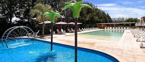 A swimming pool with two palm-shaped fountains, lounge chairs, and umbrellas.