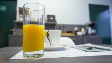 Un vaso de jugo de naranja sobre una mesa con una taza blanca y una cuchara.