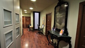 A hallway with wooden flooring, a desk with a computer, a large mirror, and a door with a wooden frame. - Hotel Annex (Barcelona)