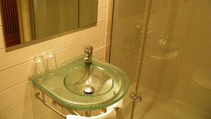 A bathroom with a glass sink, a mirror, and a glass shower enclosure. - Hotel Annex (Barcelona)