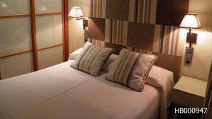 A hotel room with a bed, two pillows, a nightstand, two wall-mounted lamps, and a striped headboard. - Hotel Annex (Barcelona)