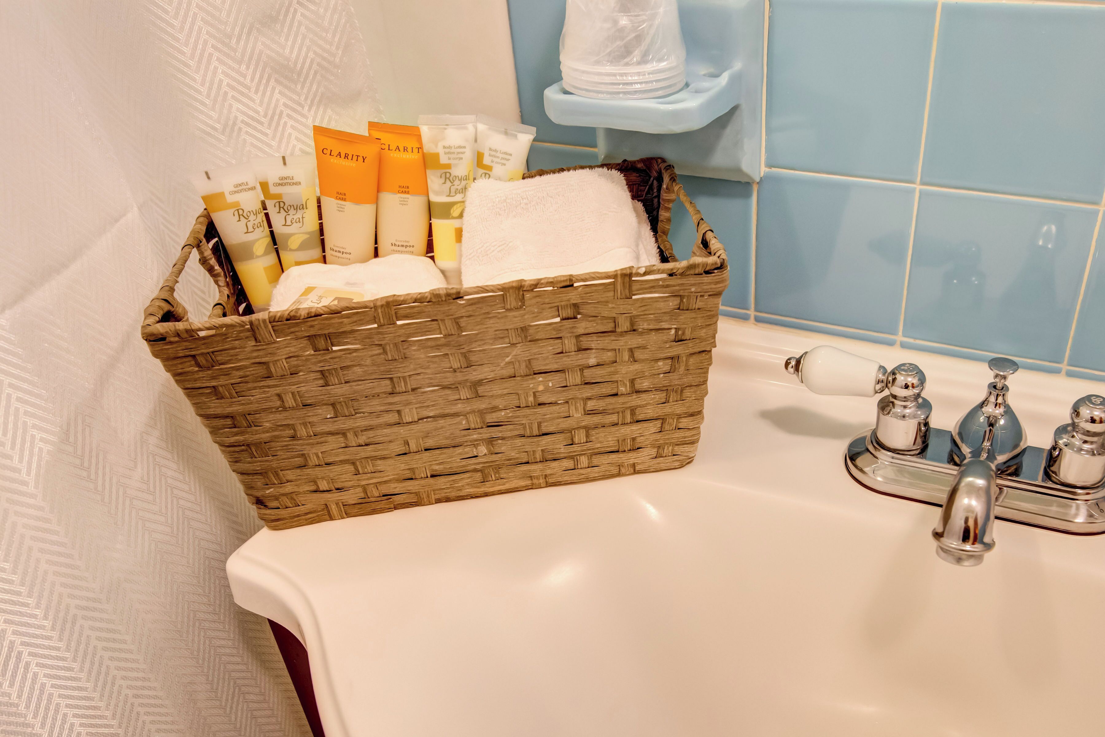 Ein Badezimmer mit einem Korbbad, Kosmetikartikeln und einem weißen Handtuch auf einem Waschbecken.