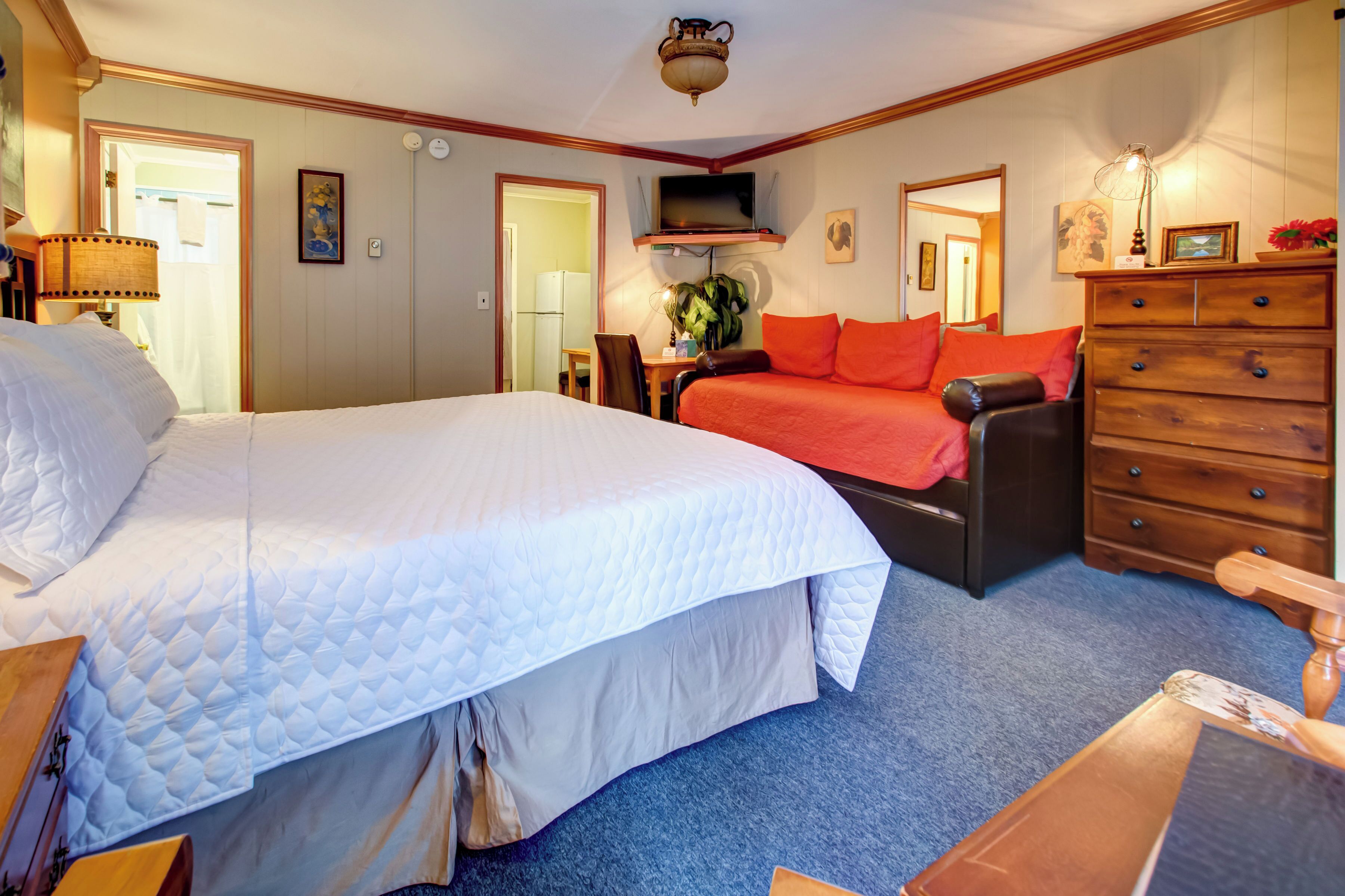 A hotel room with a large bed, a sofa, a dresser, and a television.