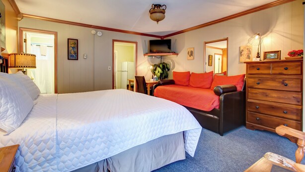 A hotel room with a large bed, a sofa, a dresser, and a television. - Starlite Motel (Big Indian)