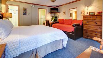 A hotel room with a large bed, a sofa, a dresser, and a television.