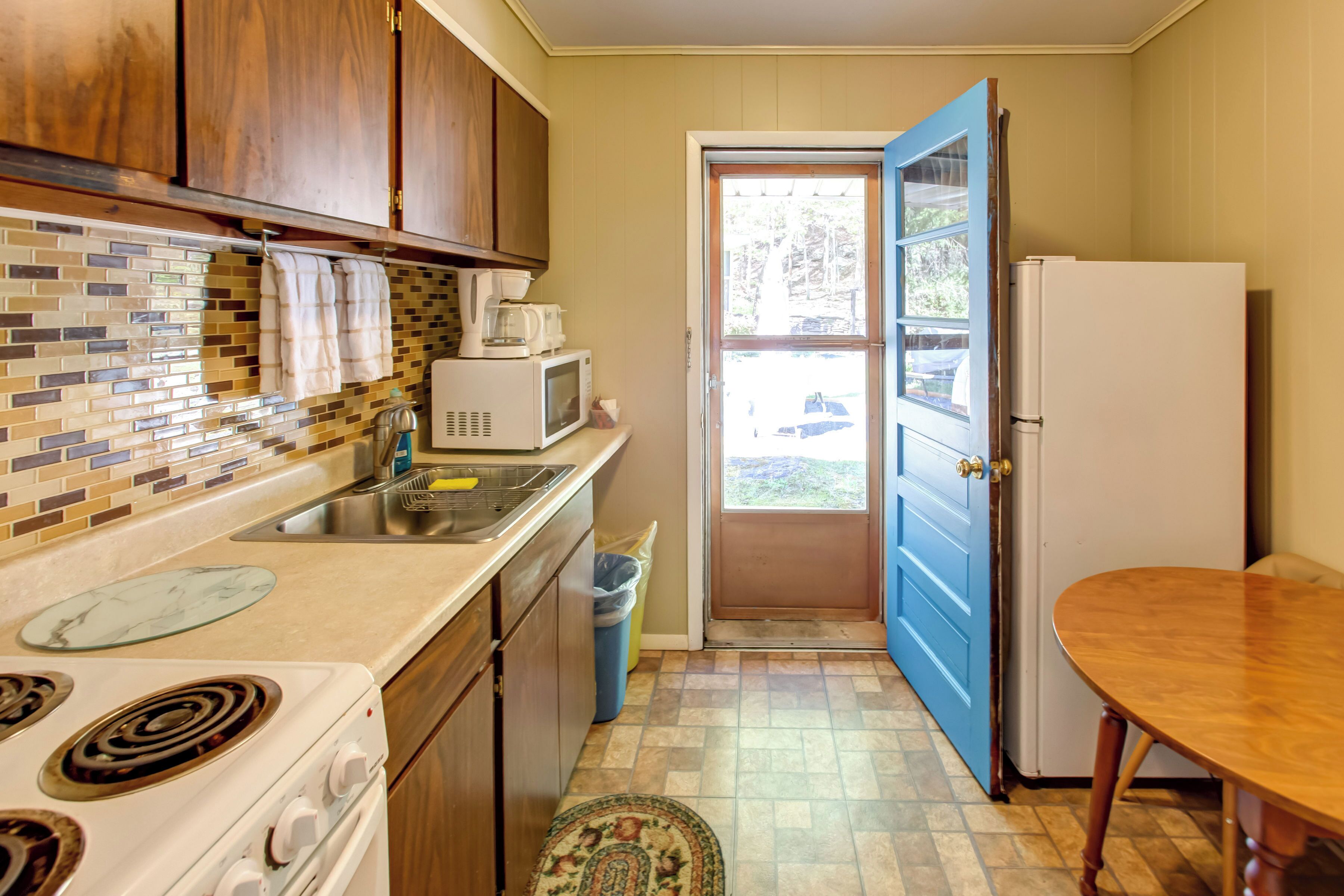 A kitchen with wooden cabinets, a white stove, a microwave, and a refrigerator.