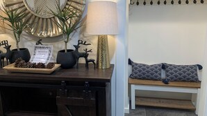 A reception desk with a mirror, potted plants, a welcome sign, and a bench with patterned cushions. - Starlite Motel (Big Indian)