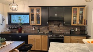 A modern kitchen with dark cabinets, a brick backsplash, and a central island. - Starlite Motel (Big Indian)