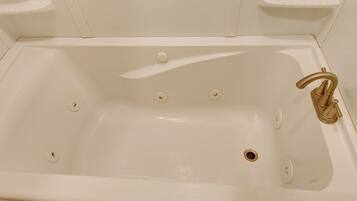 A white bathtub with a single gold faucet, four drain holes, and a single plug.