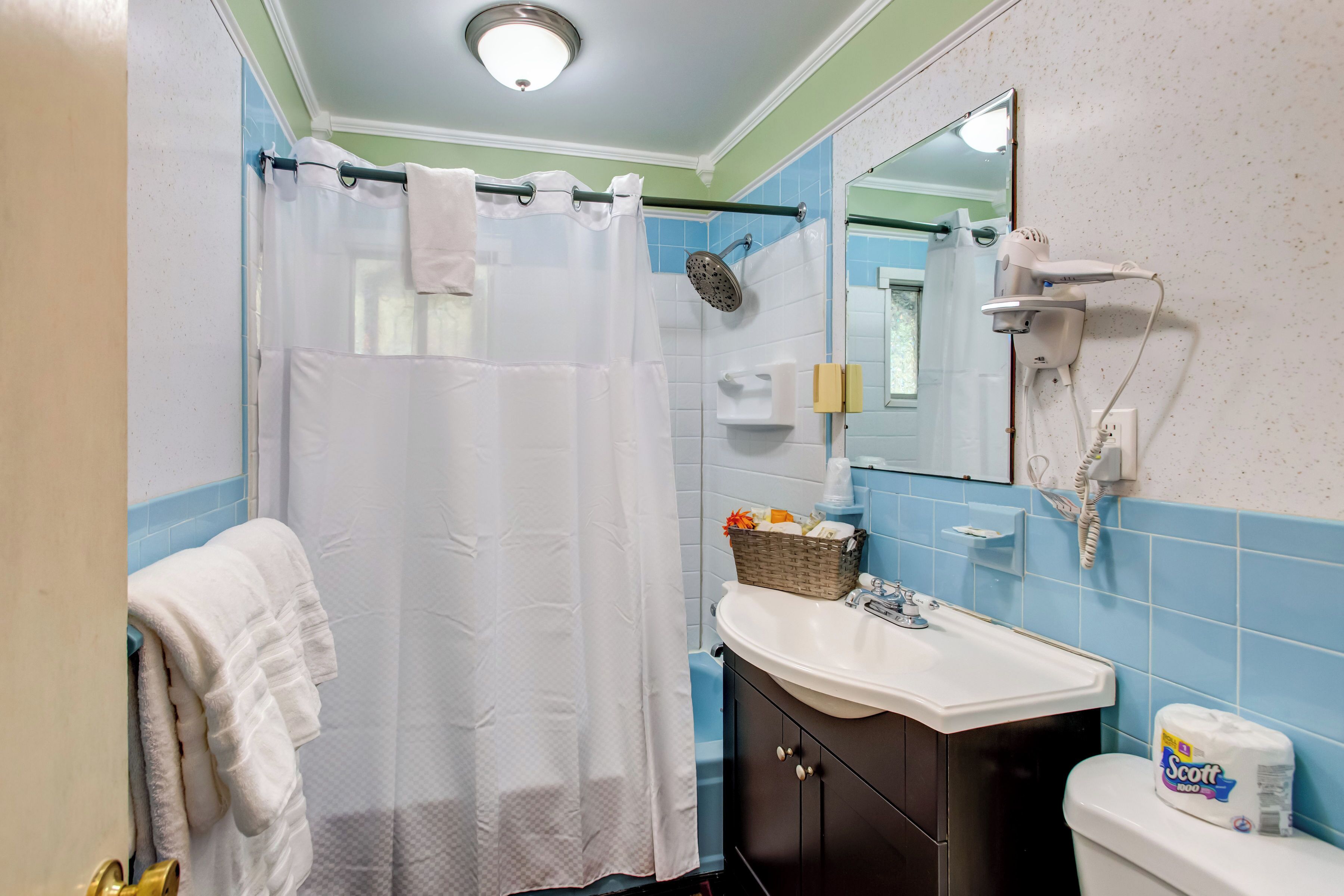 A bathroom with a shower, a sink, a toilet, and a mirror.
