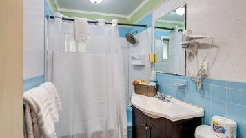 A bathroom with a shower, a sink, a toilet, and a mirror.