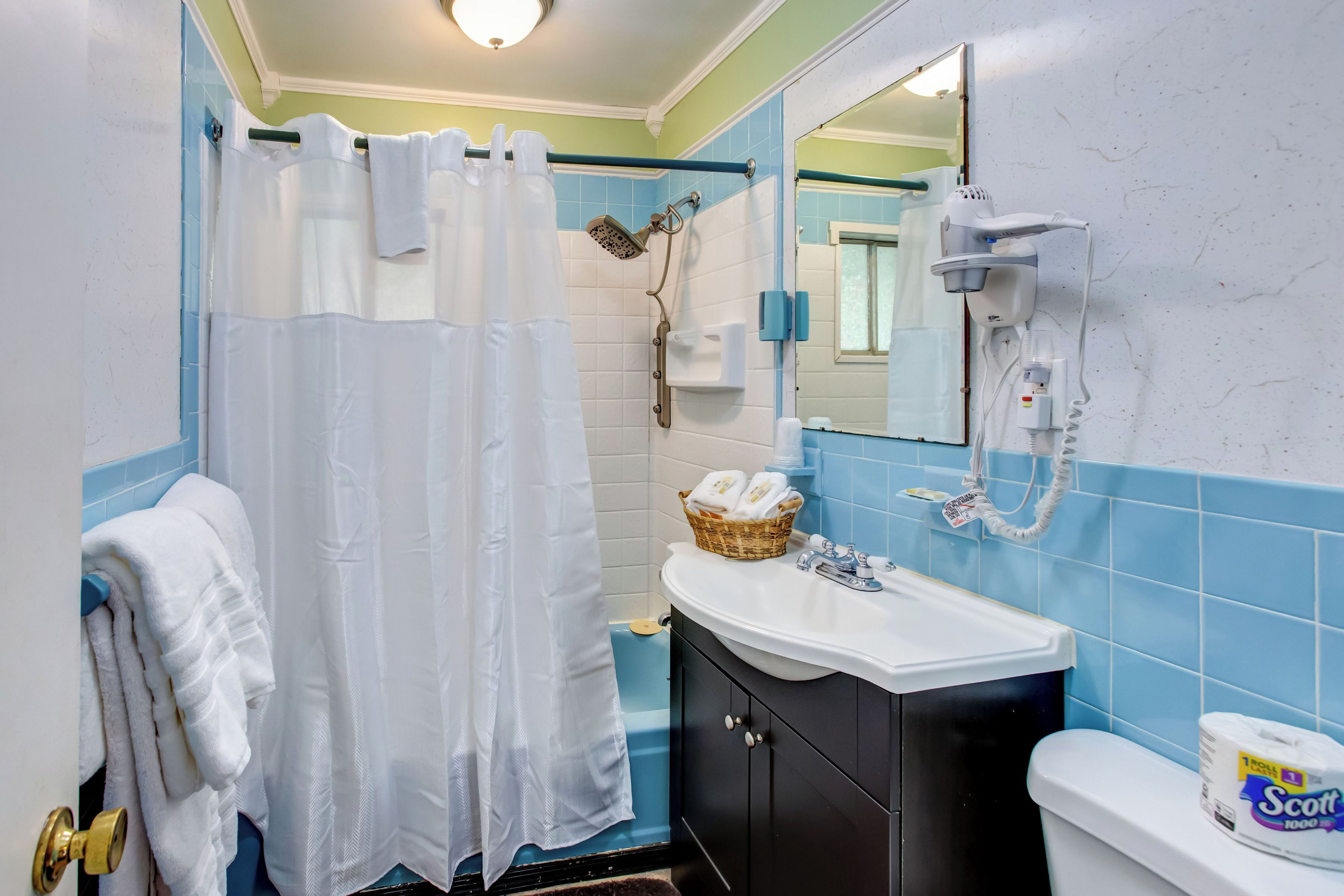 A bathroom with a shower, a sink, a toilet, and a mirror.