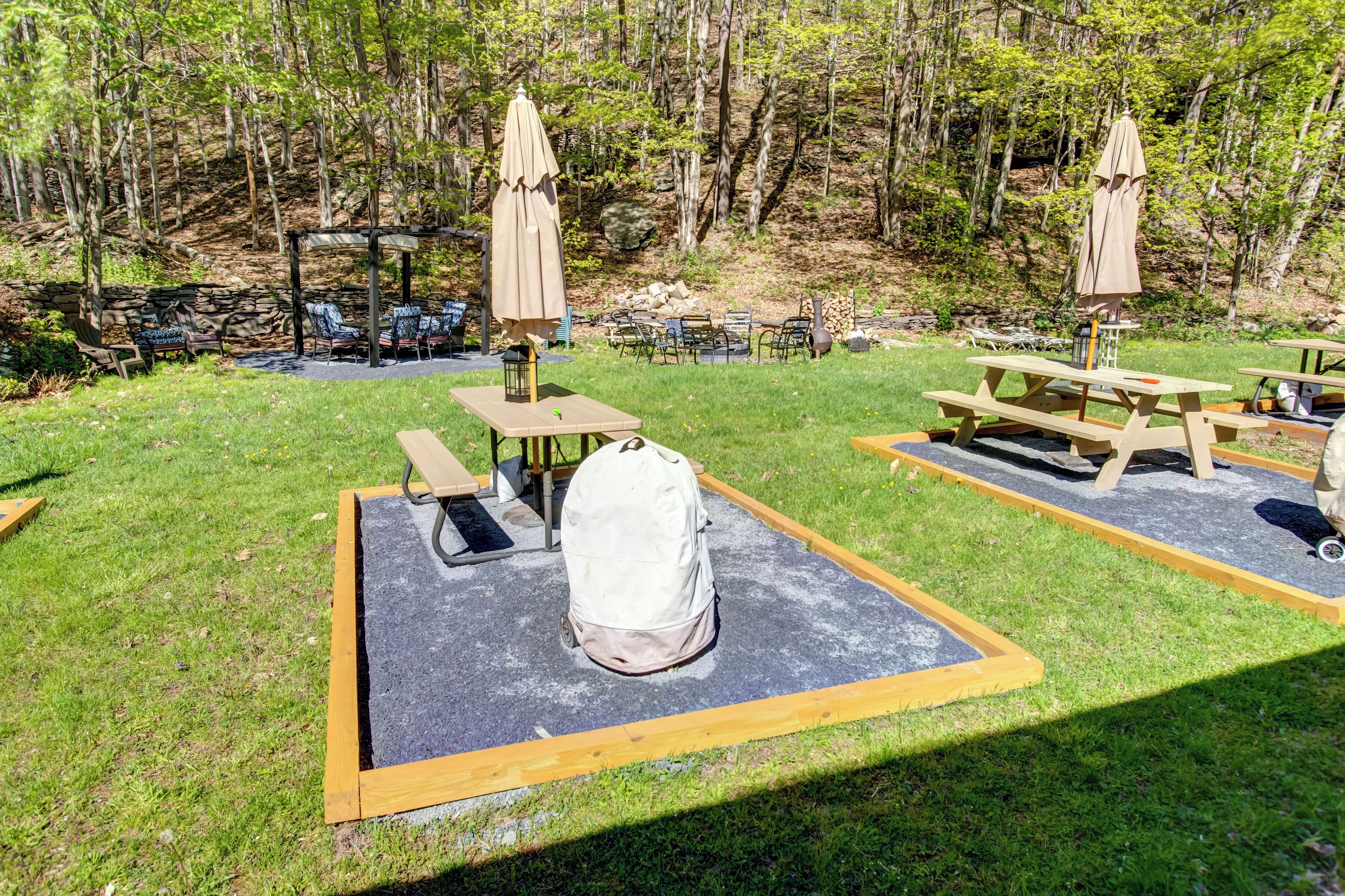Un área de picnic con mesas y sillas, rodeada de árboles.