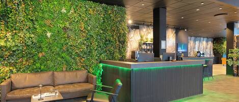 A reception area with a green wall, a reception desk, a sofa, and a chair.