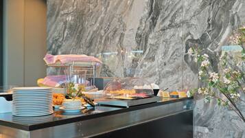Montaje tipo buffet con platos, un pastel y una presentación de frutas.