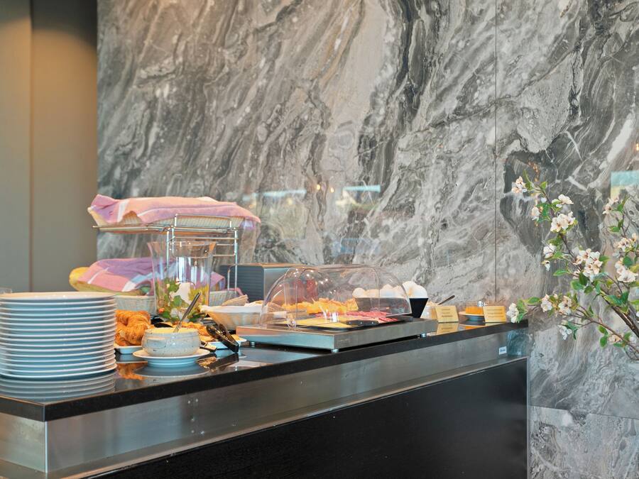 Montaje tipo buffet con platos, un pastel y una presentación de frutas.