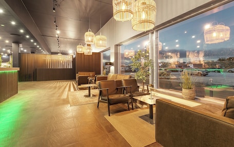 A modern hotel lobby with leather seating, large windows, and decorative lighting.
