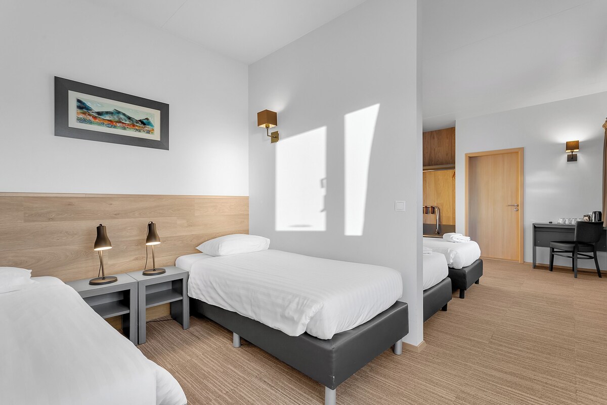 A modern hotel room with a bed, bedside tables, a desk, and a chair.