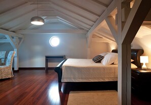 Quarto com cama, cadeira, mesa e abajur.