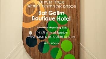 Una señal de madera con texto hebreo y el logotipo del Hotel Boutique Bat Galim, fundado con financiación del Ministerio de Turismo.