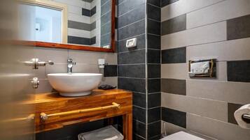 Ein Badezimmer mit einem Holzkosmetikschrank, einem weißen Waschbecken, einem Spiegel, einer Toilette und einem Handtuchhalter.
