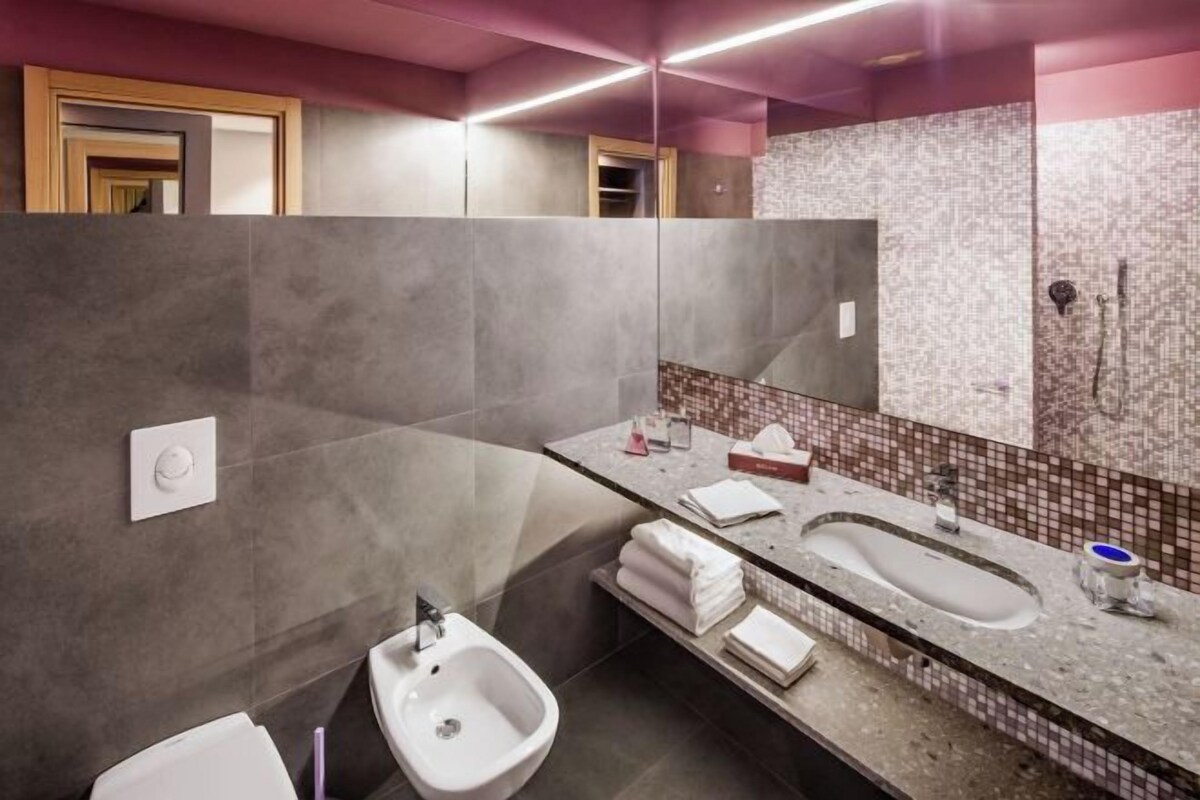 A modern bathroom with a bidet, a sink, and a mirror.