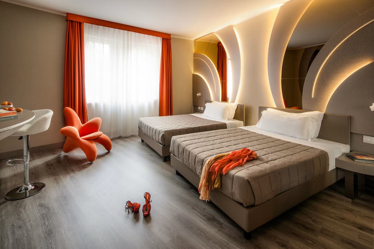 A hotel room with two beds, a desk, and a chair.
